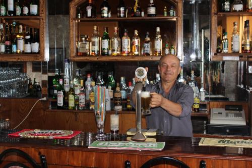 a man standing behind a bar with a drink at 75 Steps Apartments in Mesongi