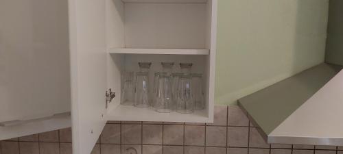 a row of glass bottles in a white cabinet at Νώε in Perístasis