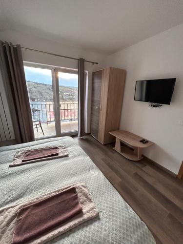 um quarto com uma cama, uma televisão e uma varanda em Giulia Home em Dezmir