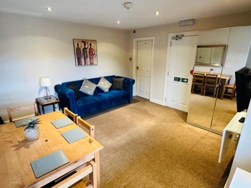 a living room with a blue couch and a table at Cheshire Hospitality Ltd Trading As Lennox Lea Studios and Apartments in Sale