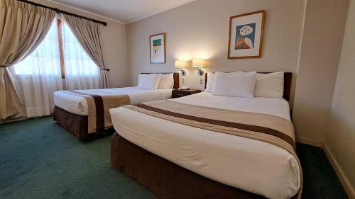 a hotel room with two beds and a window at Hotel Diego de Almagro San Pedro De Atacama in San Pedro de Atacama
