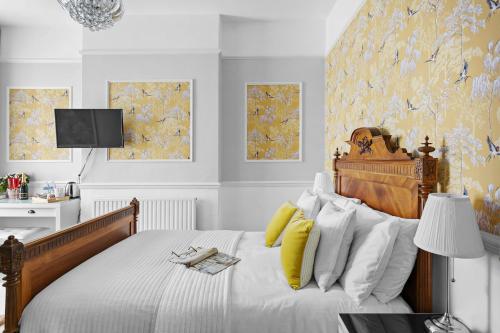 a bedroom with a bed with yellow and white pillows at Sandway House in Torquay