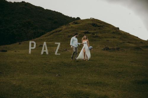 a bride and groom walking in a field with a sign at Cabana Refúgio - Pousada Colina dos Ventos in Urubici