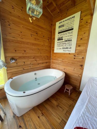 Cette chambre dispose d'une baignoire et d'un mur en bois. dans l'établissement Cabana Refúgio - Pousada Colina dos Ventos, à Urubici