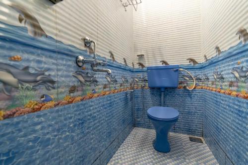 een badkamer met een blauw toilet en een muurschildering van eenden bij Whoopers Hostel Anjuna, Goa in Anjuna