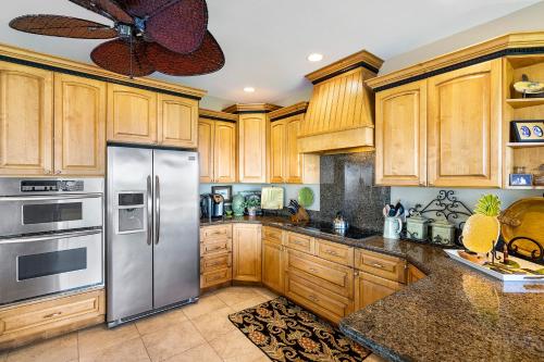 a kitchen with wooden cabinets and a stainless steel refrigerator at Hale Aikane in Kailua-Kona