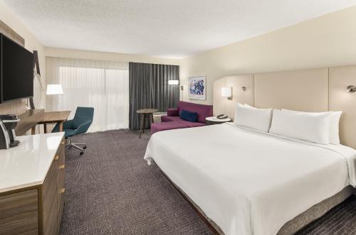 Habitación de hotel con cama blanca grande y escritorio. en Crowne Plaza Orlando - Lake Buena Vista, an IHG Hotel, en Orlando