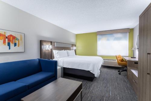 une chambre d'hôtel avec un lit et un canapé bleu dans l'établissement Holiday Inn Express Hotel & Suites-St. Paul, an IHG Hotel, à Vadnais Heights