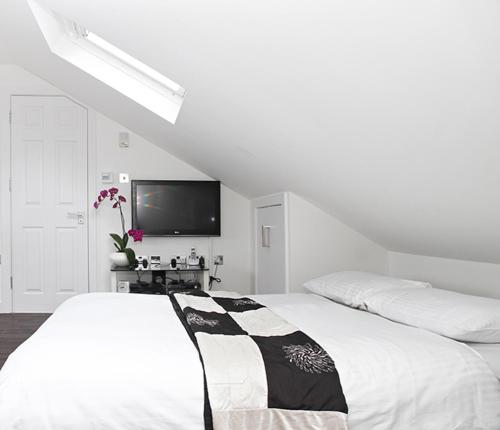 a white bedroom with a bed and a flat screen tv at Holiday Lets London - I5 in London