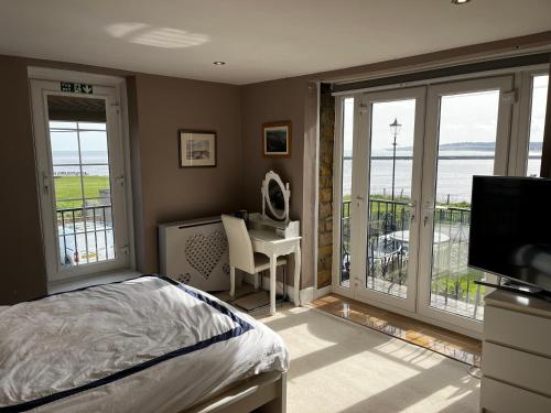 a bedroom with a bed and a desk and a balcony at The View in Tynemouth