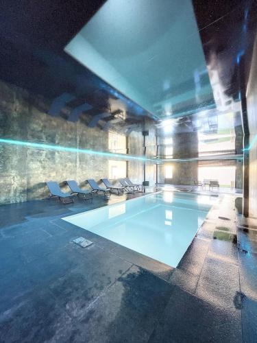 - une piscine avec des chaises blanches dans un bâtiment dans l'établissement Villa 400m2 piscine intérieure très calme, à Agde