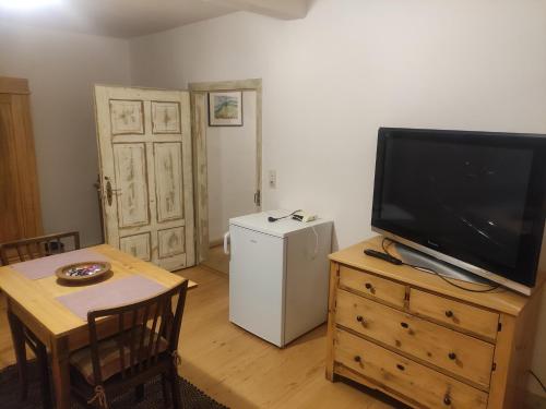 a living room with a television on a dresser and a table with a small at Zimmer A Veljanovski in Blaufelden