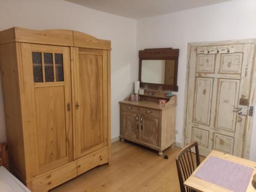 a room with a wooden cabinet and a mirror and a table at Zimmer A Veljanovski in Blaufelden