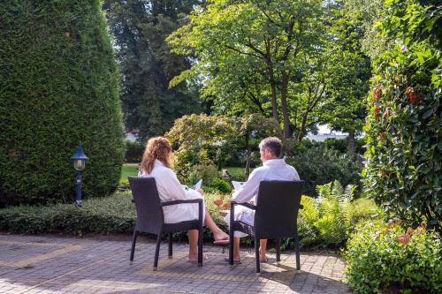 a man and woman sitting in chairs in a garden at Boetiek Hotel BonAparte Lochem in Barchem
