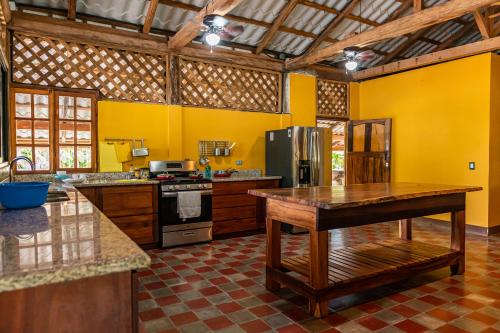 a large kitchen with yellow walls and a refrigerator at Casa Hacienda El Menco in Rivas