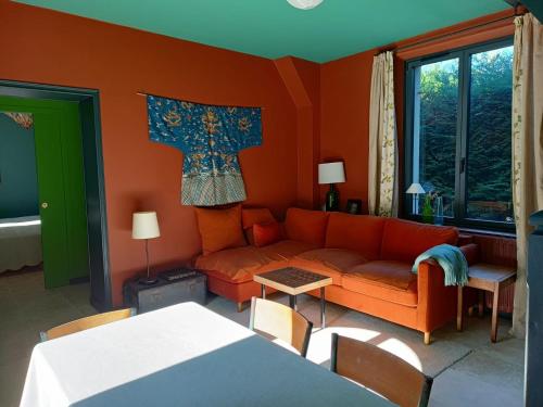 ein Wohnzimmer mit einem orangenen Sofa und einem Tisch in der Unterkunft Le petit Ermitage in Méré