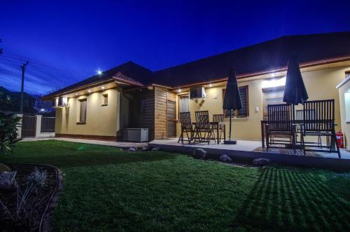a house with chairs and umbrellas in a yard at night at Paradiso Apartmanház in Gyula