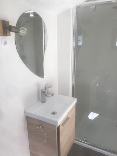 une salle de bain blanche avec un lavabo et un miroir dans l'établissement Maisonnette 2 pièces 100m de la plage de la Clère, à Le Grand Vieil