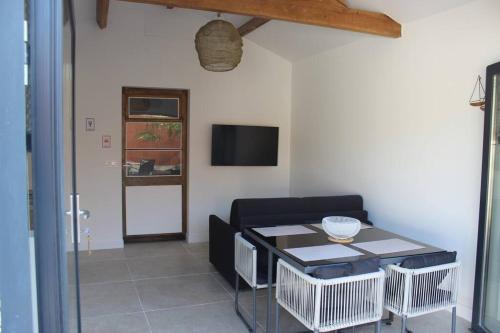 een woonkamer met een tafel en een televisie bij Maisonnette 2 pièces 100m de la plage de la Clère in Le Grand Vieil
