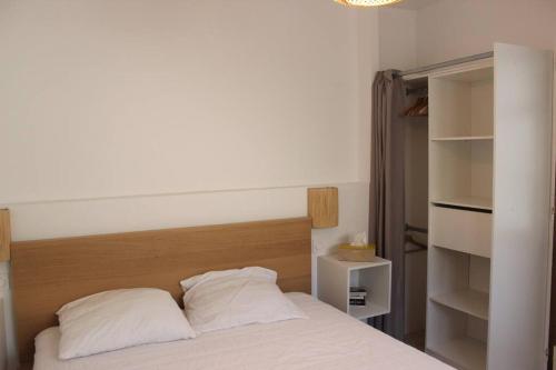 een bed met 2 kussens in een slaapkamer bij Maisonnette 2 pièces 100m de la plage de la Clère in Le Grand Vieil