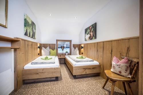 two beds in a room with wooden walls at Oberhaslachhof in Reith im Alpbachtal
