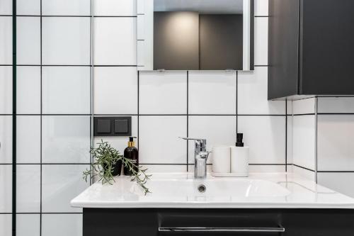 a white bathroom with a sink and a mirror at River To The City - Studio 7b Apartment in Vilnius