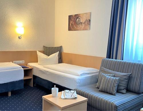 Habitación de hotel con 2 camas y sofá en Hotel Bettina garni, en Günzburg