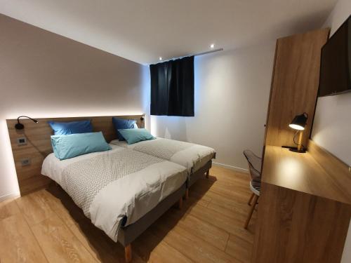 une chambre avec un lit avec des oreillers bleus dans l'établissement Alpamayo, appartement cosy au coeur des Aravis, à Les Villards-sur-Thônes