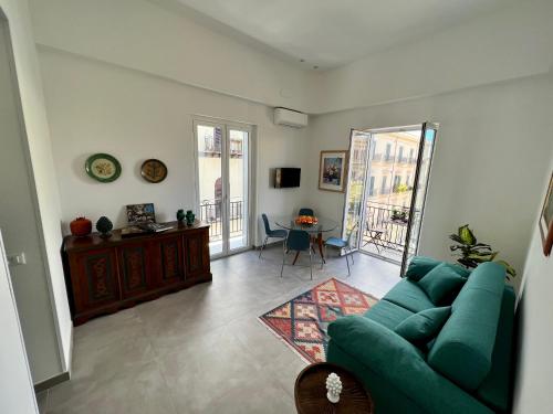 ein Wohnzimmer mit einem grünen Sofa und einem Tisch in der Unterkunft Case Orlando_a city center Sicilian treat in Palermo