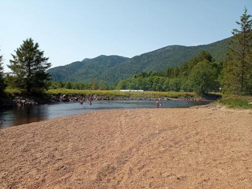 un grupo de personas de pie en una playa al lado de un río en Leilighet på gård, en Sauland