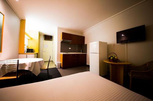 a small room with a kitchen with a table and a refrigerator at Sandown Regency Hotel & Apartments in Noble Park