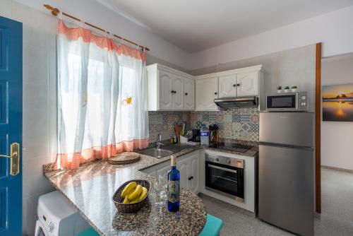 a kitchen with a counter with a sink and a refrigerator at Apartamentos con vistas al mar en El Remo in Los Llanos de Aridane