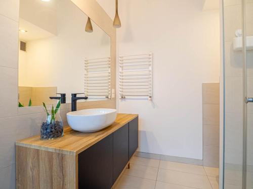 a bathroom with a white bowl sink on a wooden counter at Apartament Bocheńska in Krakow