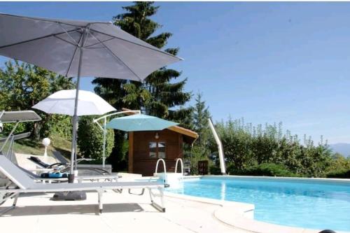 a pool with chairs and umbrellas next to a swimming pool at La Villa Jo in Le Grand-Lemps