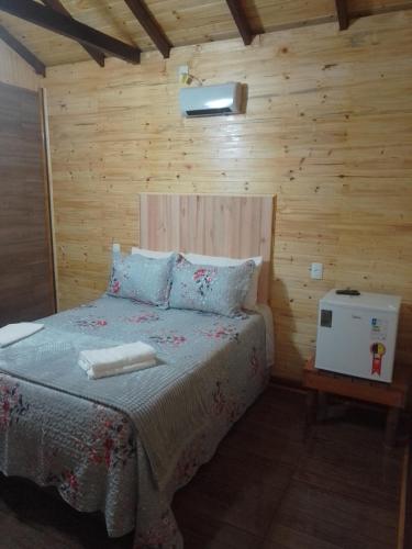 a bedroom with a bed in a wooden room at cabanas paisagem da serra in Urubici