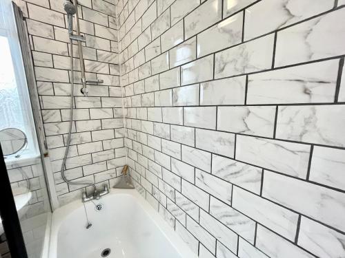 a bathtub in a bathroom with white subway tiles at City Haven Luxurious 3-Bed Retreat in Portsmouth