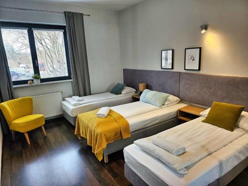um quarto de hotel com três camas e uma cadeira em Apartamenty Arkadia by VisitWarsaw Apartments em Varsóvia