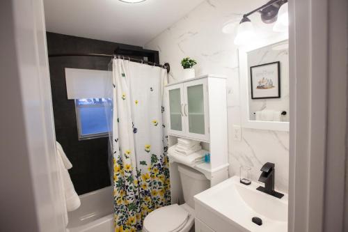 Baño blanco con cortina de ducha y lavamanos en Alafia- Cozy JFK Area Home - This property is a hosted property meaning the host live on site en Locust Manor
