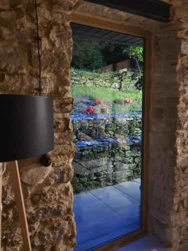 a window with a view of a stone wall at AleChatki Roztocze in Huta Lubycka