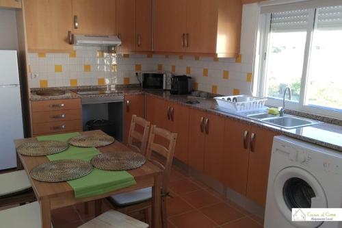 a kitchen with a table and a washing machine at Casa D'Avó (1º Andar) in Altura