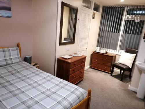 a bedroom with a bed and a dresser and a mirror at Pensalda Guest House in Newquay