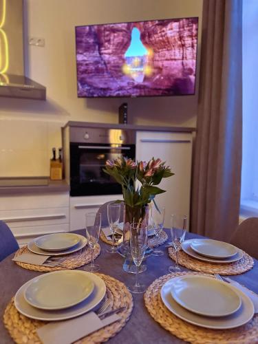 a dining room table with plates and glasses and a tv at Ferienwohnung Strandläufer in Wilhelmshaven