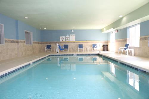 a large swimming pool with blue chairs in it at Holiday Inn Express Hotel & Suites Albuquerque Airport, an IHG Hotel in Albuquerque
