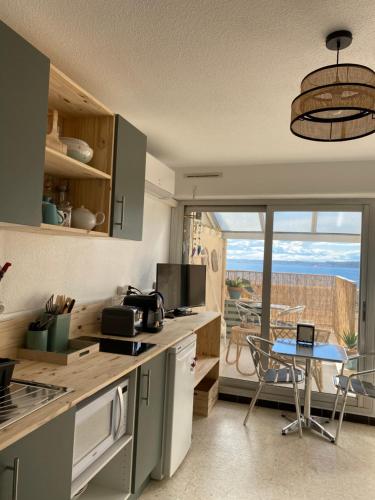 una cucina con tavolo e vista su un balcone di Les reflets de l'étang a Balaruc-les-Bains