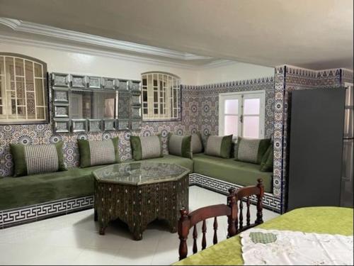 ein Wohnzimmer mit einem grünen Sofa und einem Tisch in der Unterkunft Appartement chems in Oualidia