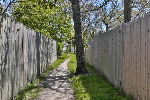 a fence with a tree next to a dirt road at 557 Route 28, Unit 202, Harwich Port Cape Cod - -Dolce Vita in Harwich Port