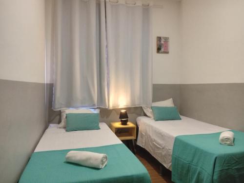 2 Betten in einem Zimmer mit Grün und Weiß in der Unterkunft Apartamento encantador in Belo Horizonte