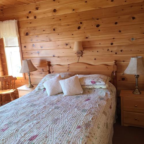 1 dormitorio con 1 cama con pared de madera en Sleepy Pines Oceanfront Cottages, en Cumberland