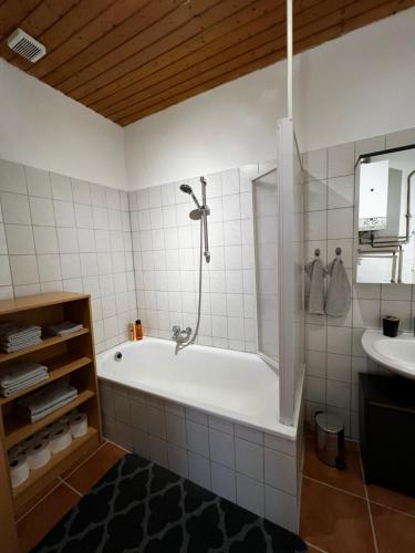 ein weißes Badezimmer mit einer Badewanne und einem Waschbecken in der Unterkunft Altstadtperle-Herz der Altstadt in Kaiserslautern