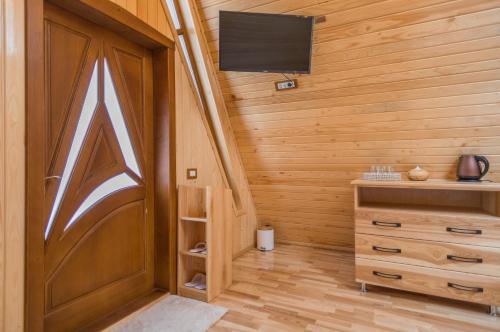 a room with a wooden door and a tv at Arhico Cabins in Satu Mare